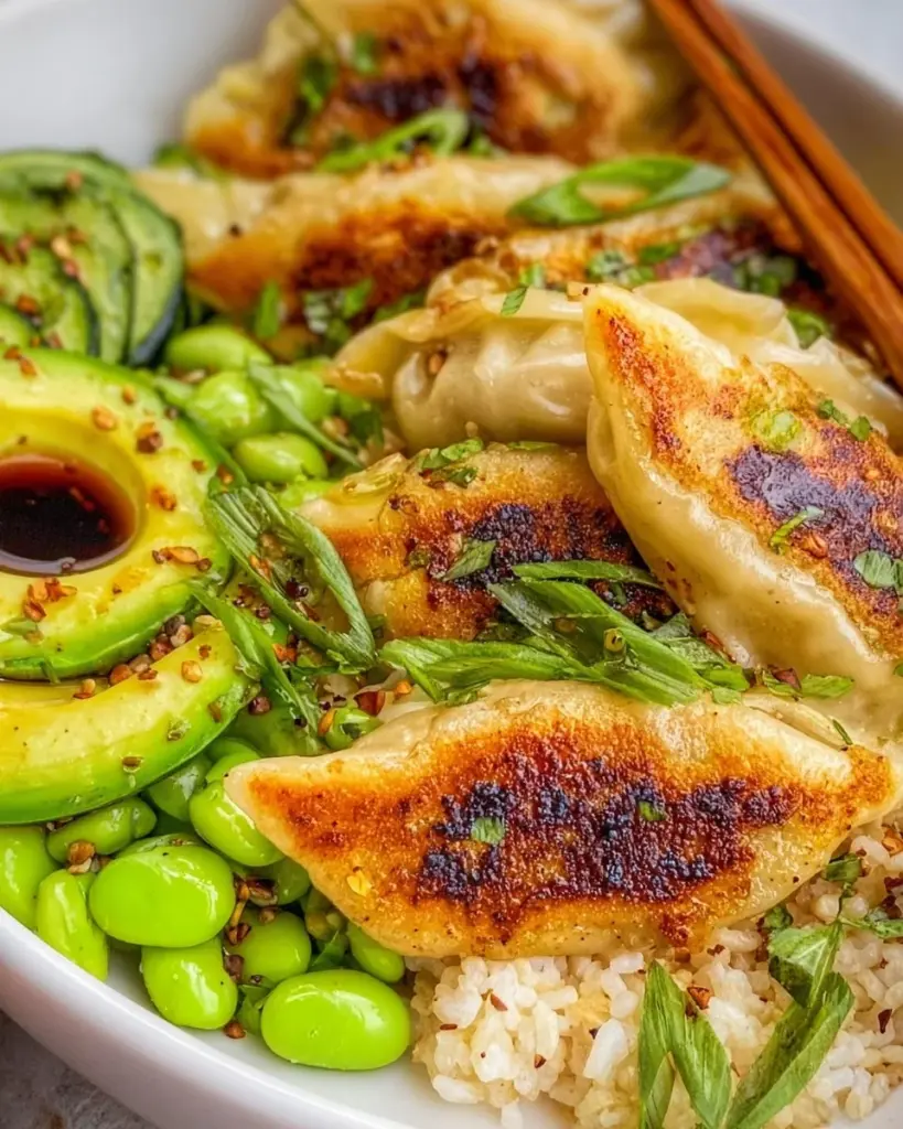A bowl filled with potstickers and colorful vegetables, showcasing a delicious meal.