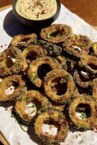 Crispy zucchini rings served with creamy zucchini dip on a plate